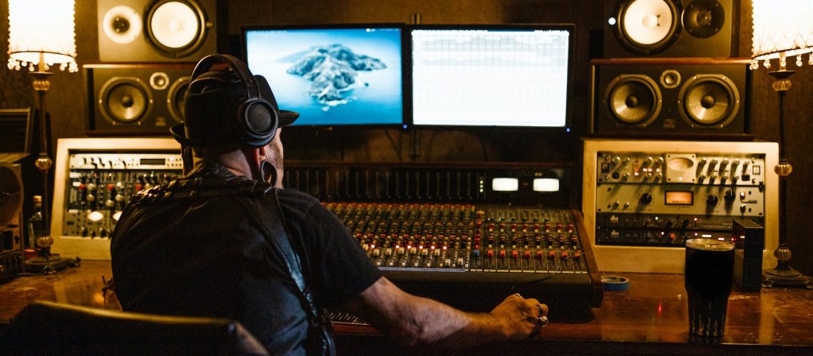 man in black shirt wearing headphones in front of monitors